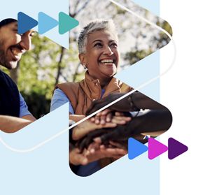 Smiling diverse team members stack hands in a collaborative gesture in a sunny park, conveying teamwork, unity, and shared enthusiasm.